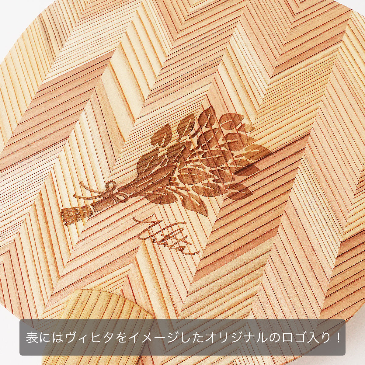 木製うちわの表面にレーザー刻印された、植物（ヴィヒタ）をモチーフにしたオリジナルロゴ